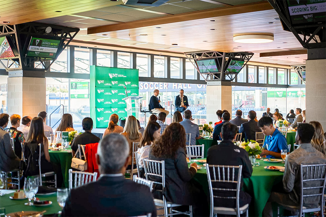 Heere and FC Dallas owner Dan Hunt speaking at the 2024 Ryan College of Business Business Matters Luncheon.