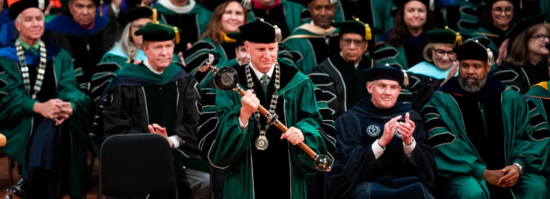 Harrison Keller holds university mace at his investiture ceremony