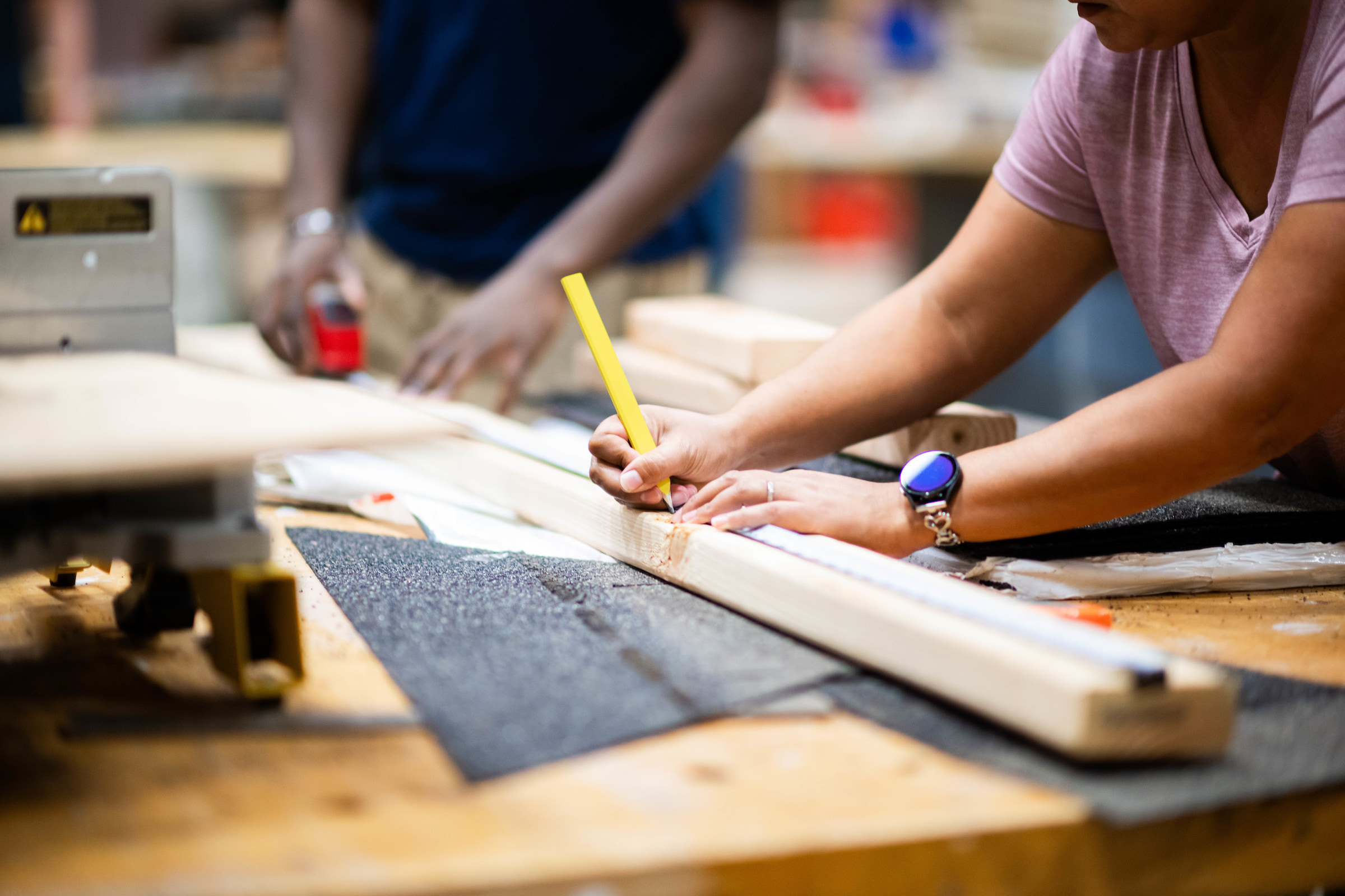 photo of a female student marking measurements on a piece of wood
