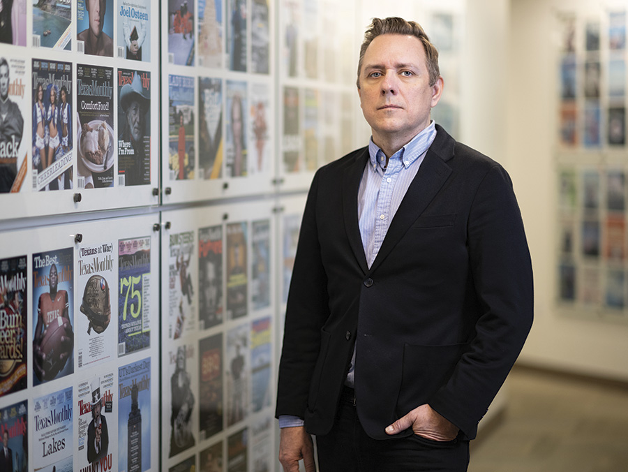 Ross McCammon posing for a portrait in front of a wall of Texas Monthly magazine covers