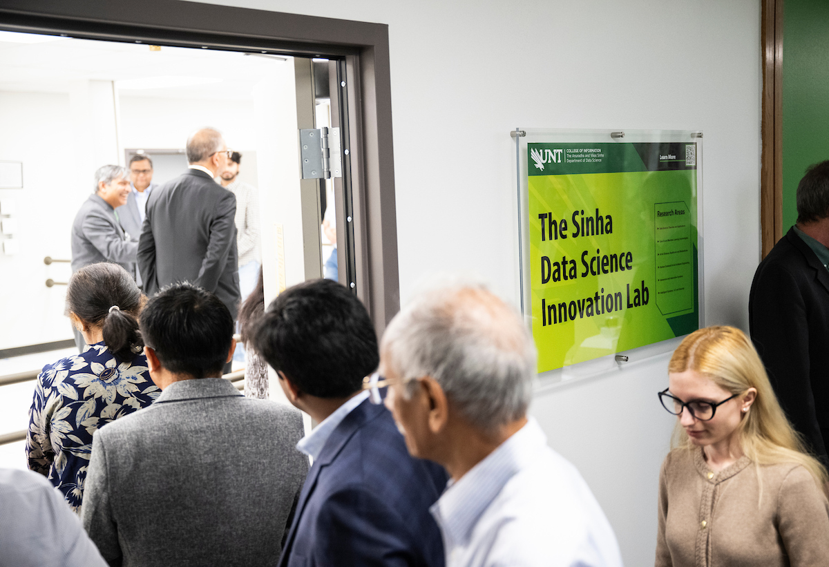 A sign on a wall reads "The Sinha Data Science Innovation Lab" as people walk past it into a room.