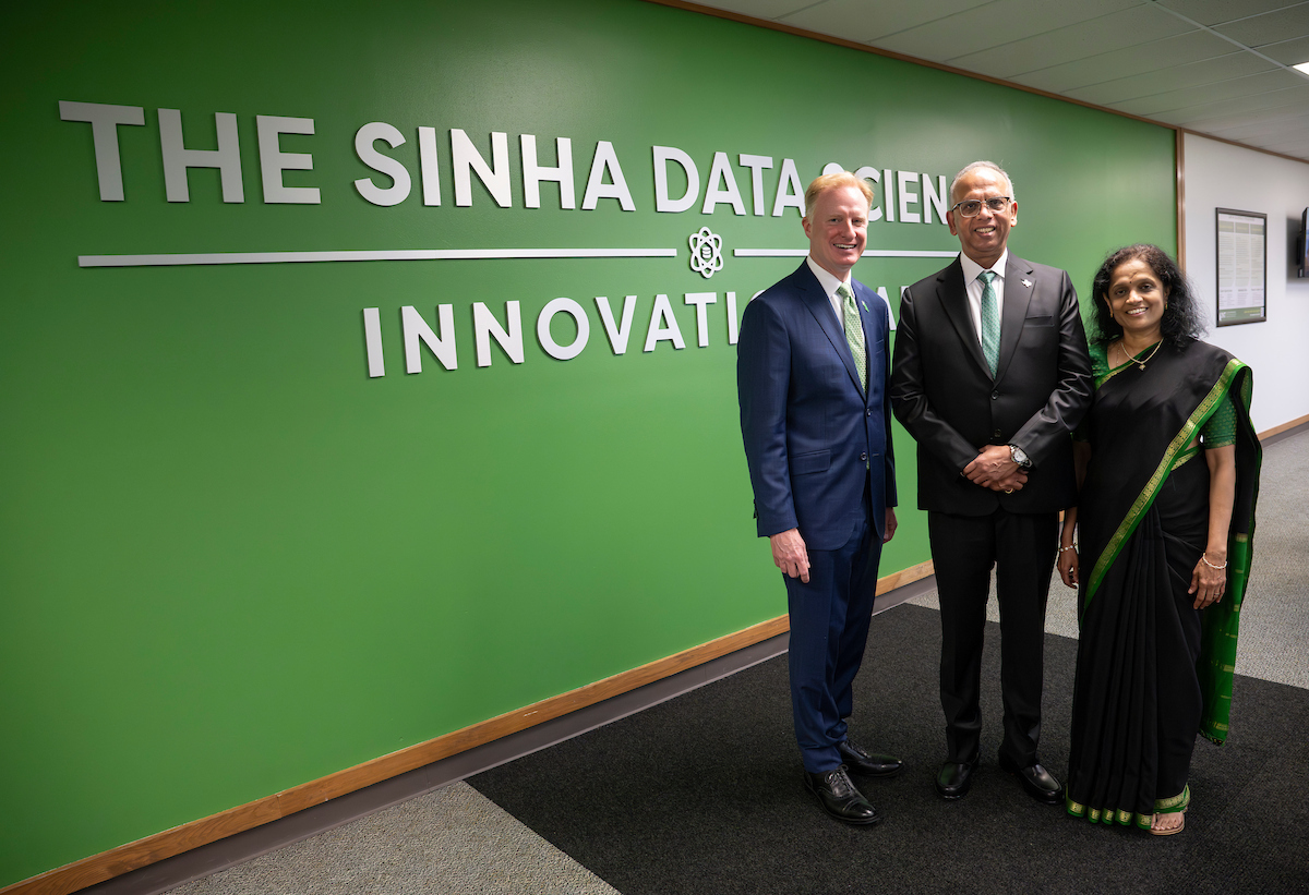 Two men and one woman stand in front of a green wall that reads "The Sinha Data Science Innovation Lab" with the text partially obscured.