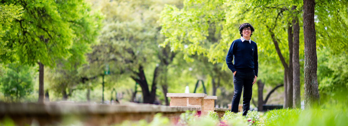 Alejandro Perez stands among green trees at the UNT Library Mall