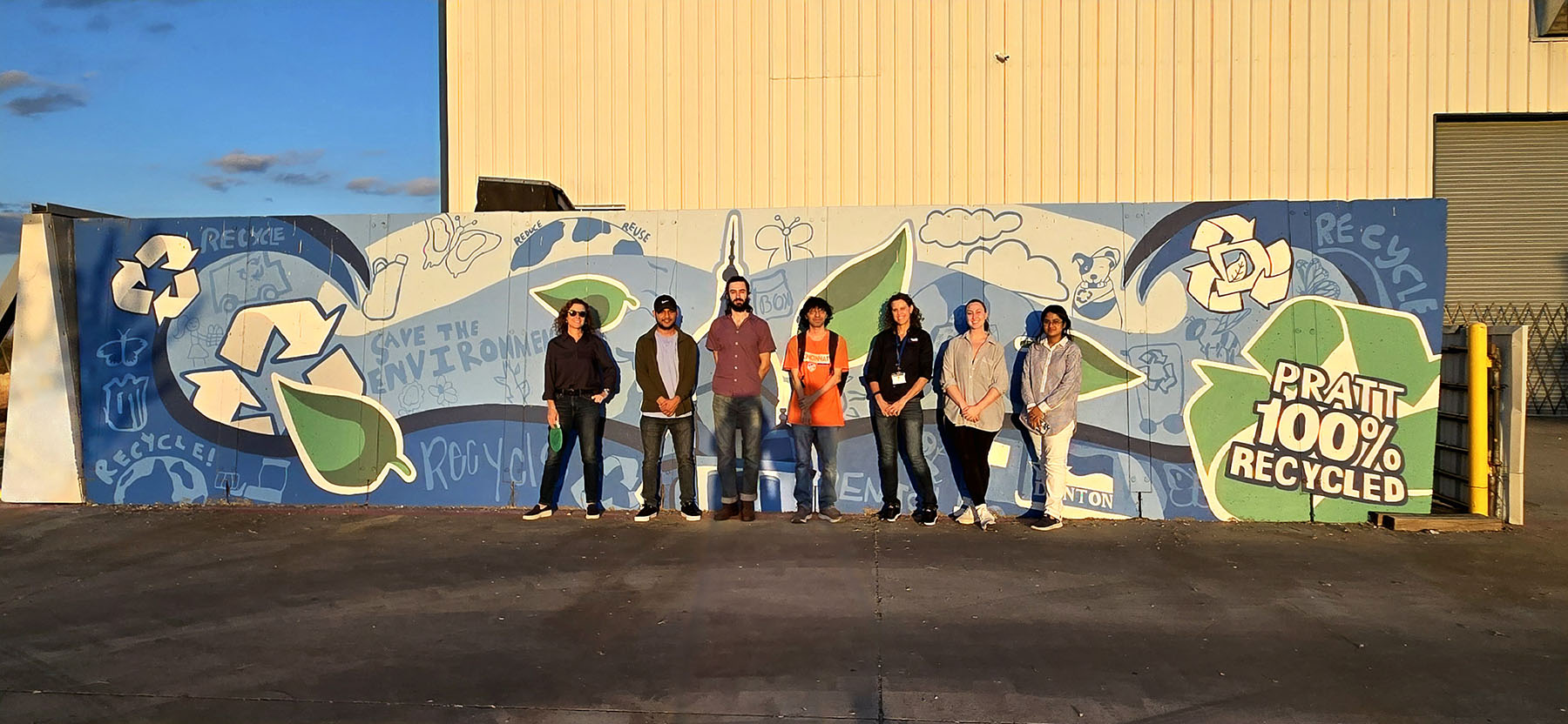 Professor Jamie Johnson and her students stand in front of a colorful mural at the Pratt Recycling Center in Denton, Texas