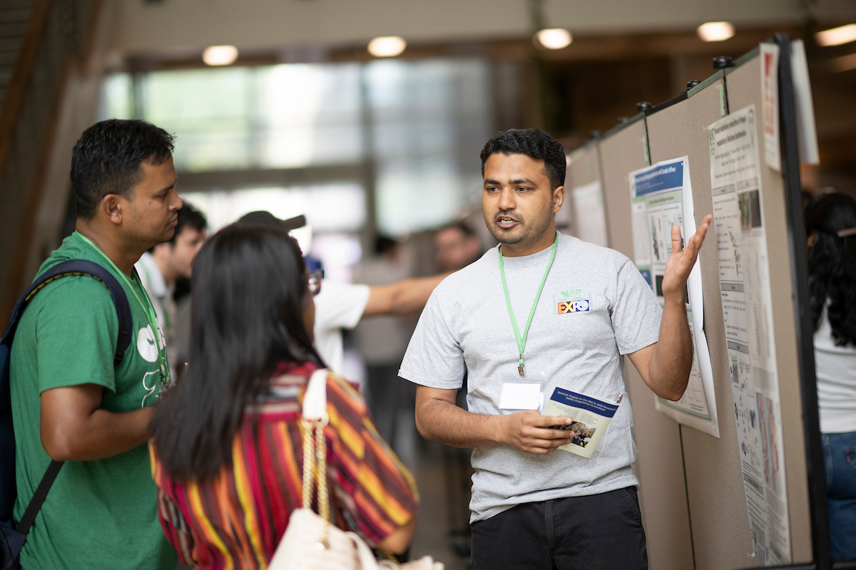 A student presents their research poster to listeners