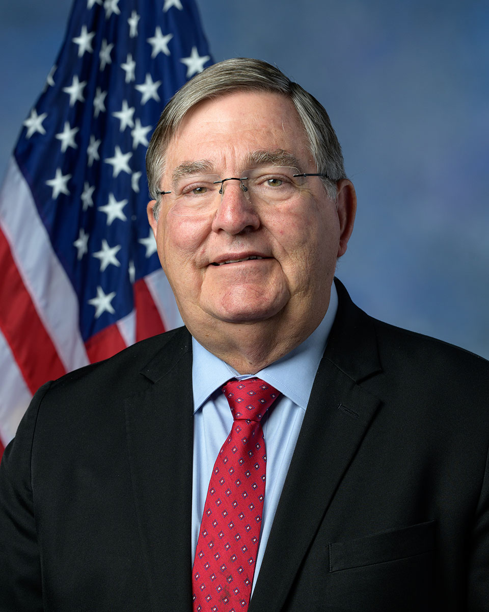 Former congressman Dr. Michael Burgess poses in front of the American flag