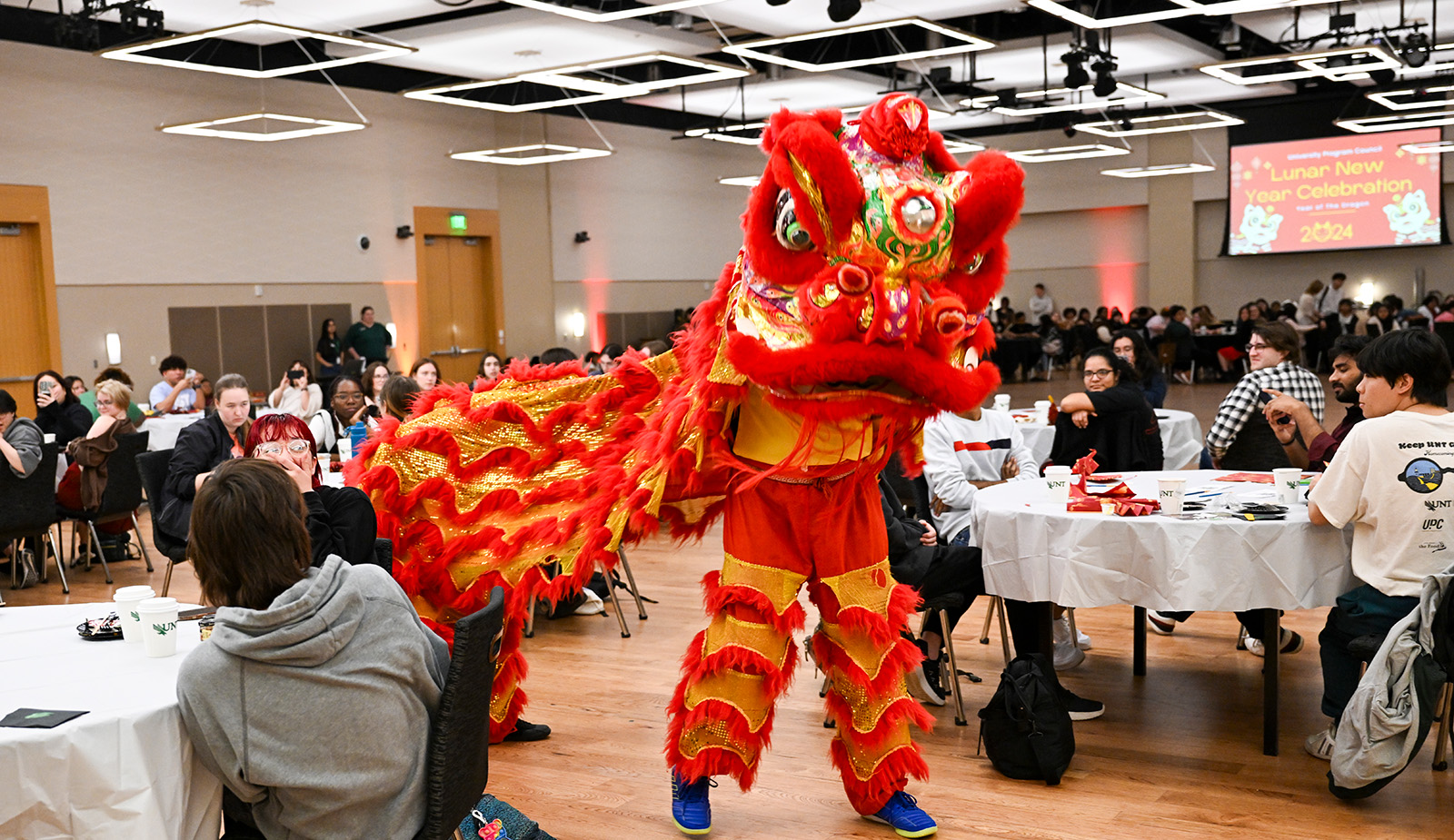 Person in a dragon costume going through a crowd of people at tables