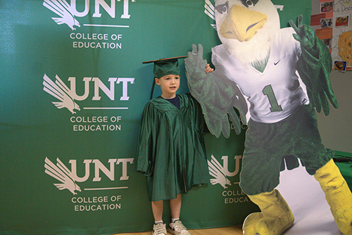 A CYC graduate stands next to a cutout of Scrappy