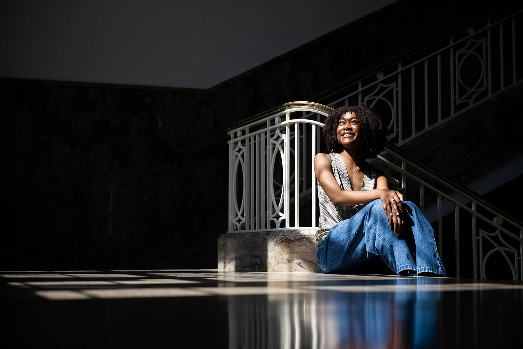 Diyah Muhammad poses seated on the inner stairwell of the Hurley Administration Building on UNT's Denton campus
