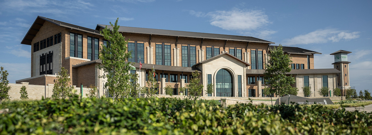 A photo of UNT at Frisco's main building with the tower next to it. A sign in front of it says "University of North Texas at Frisco."