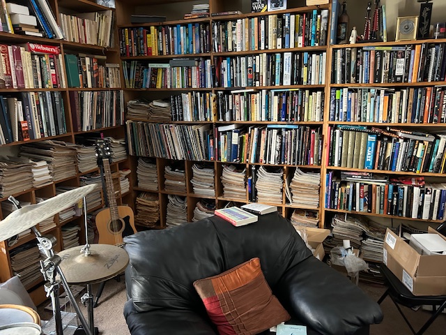 A collection of books, recordings, and magazines on office shelves.