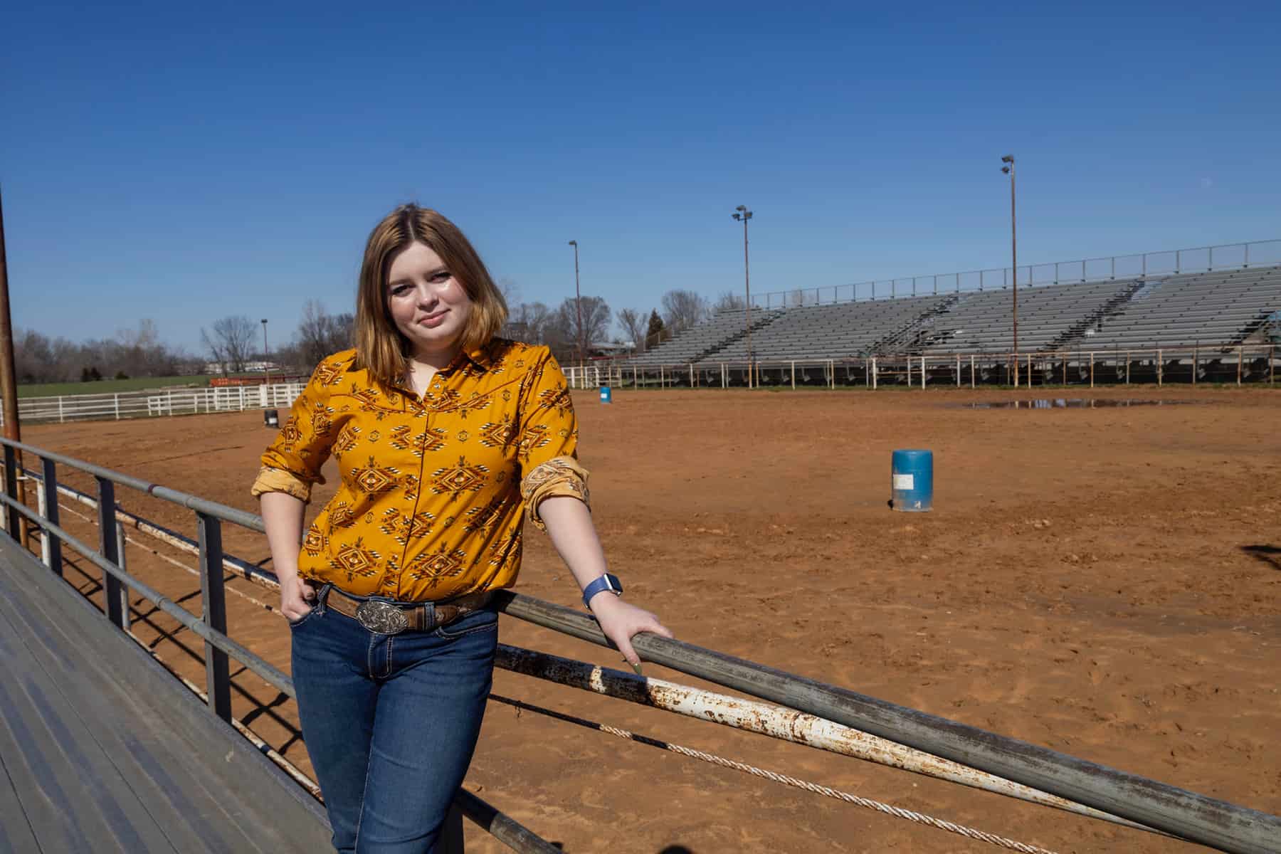 Lauren Sicking stands outside near a rodeo arena