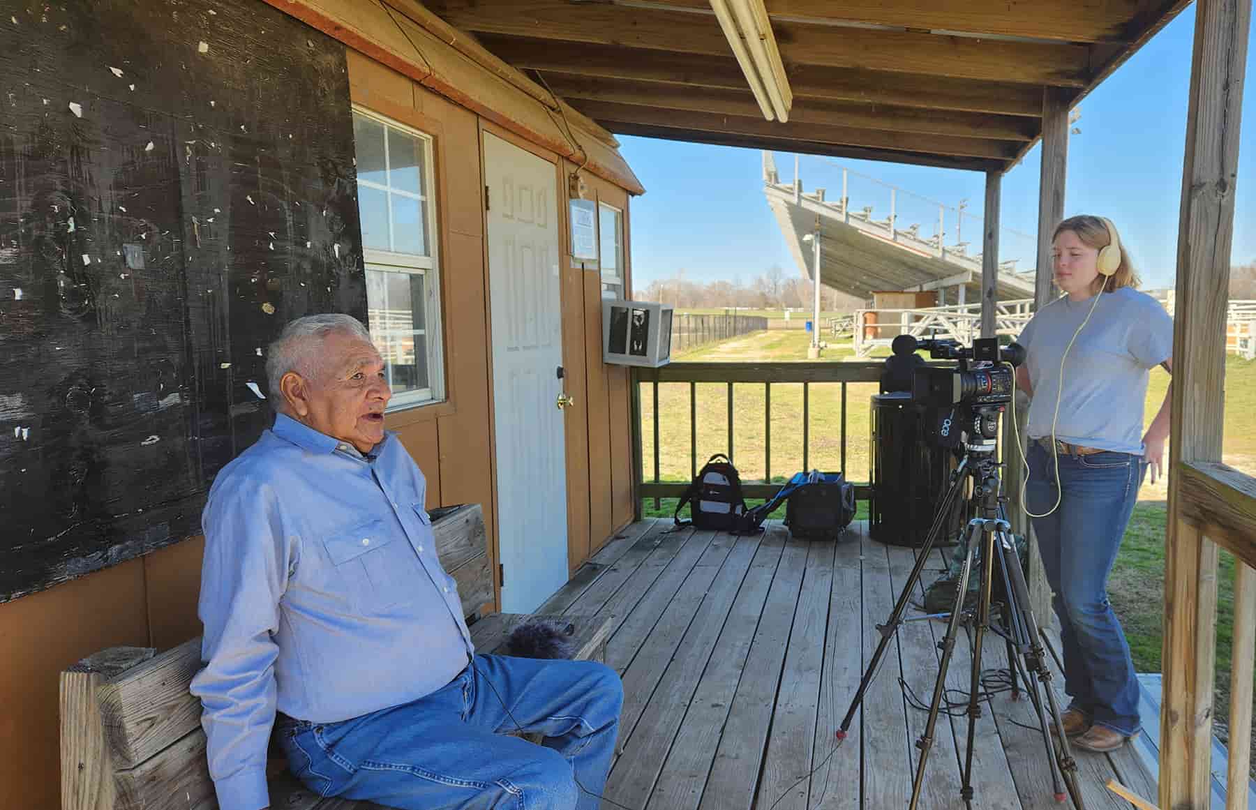 Student interviews resident of Okmulgee, Oklahoma, outside near a rodeo arena