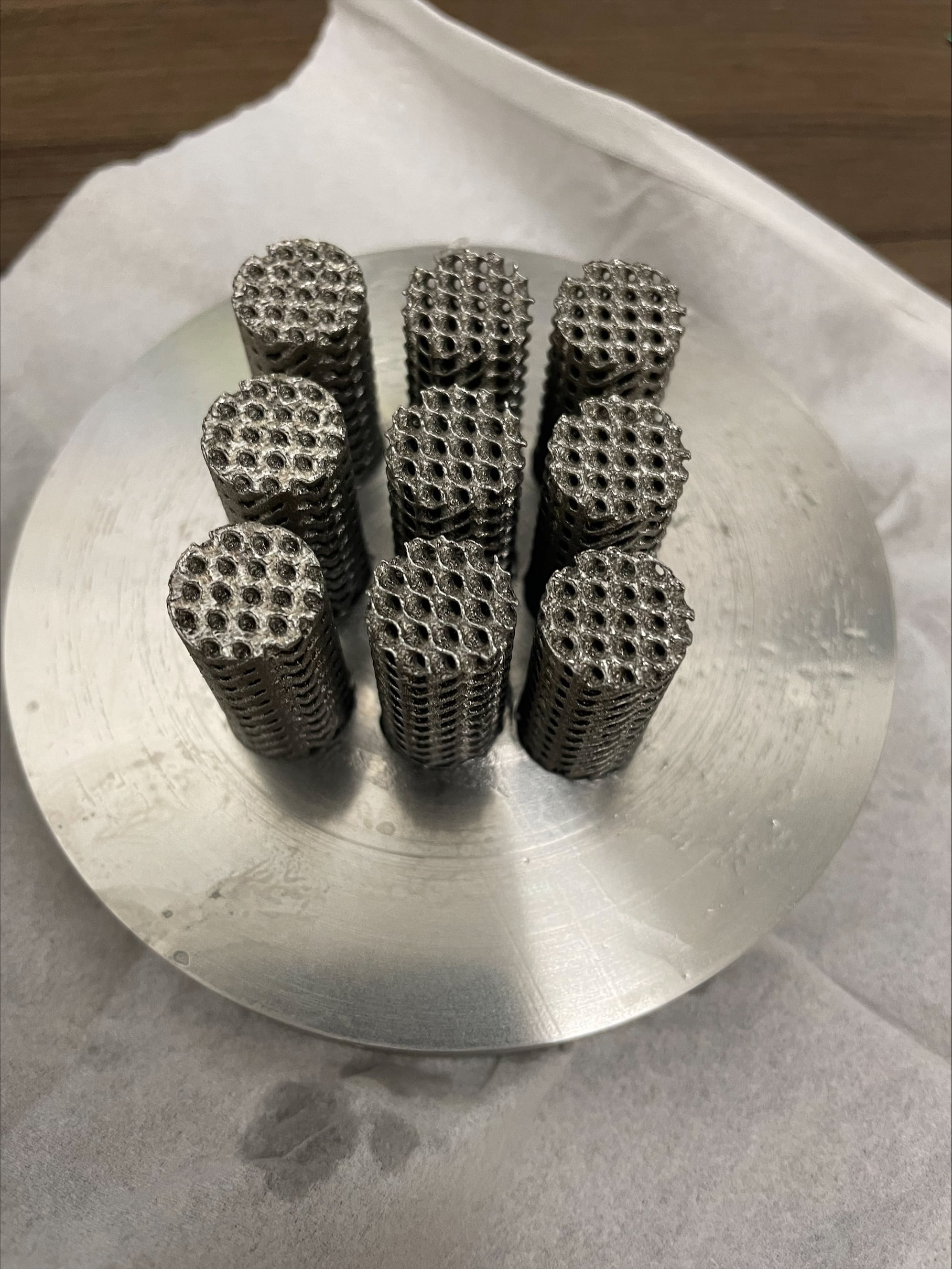 Nine additive manufactured stainless steel cylinders with a lattice framework