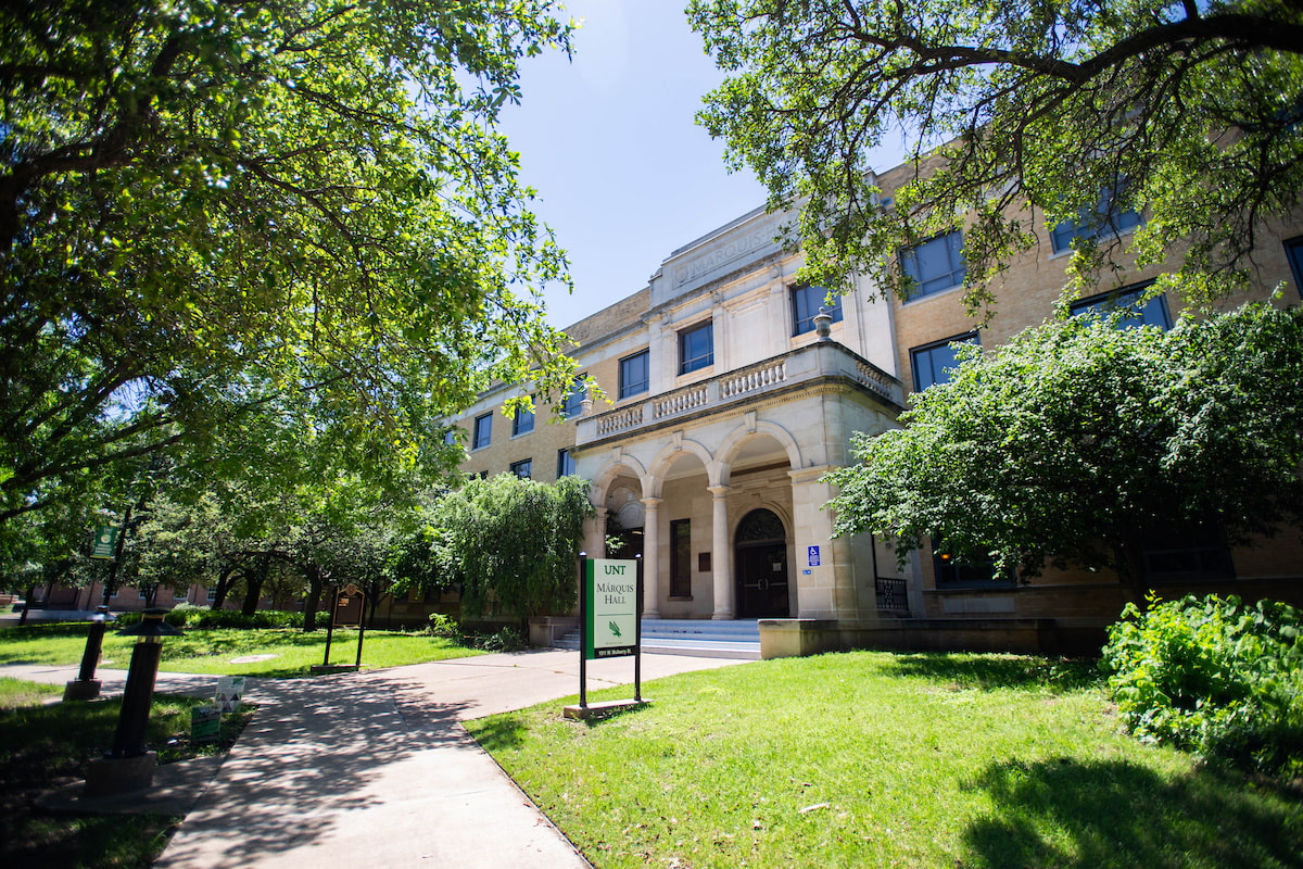 The Marquis Hall building on a clear sunny day surrounded by green trees