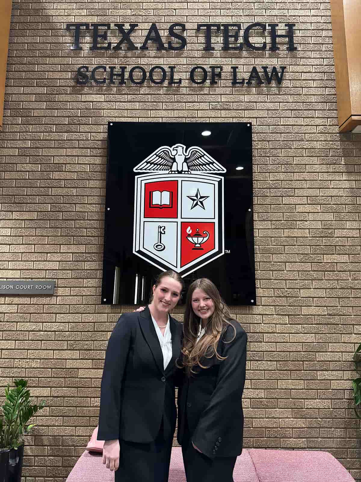 Two students pose in front of a sign for Texas Tech School of Law