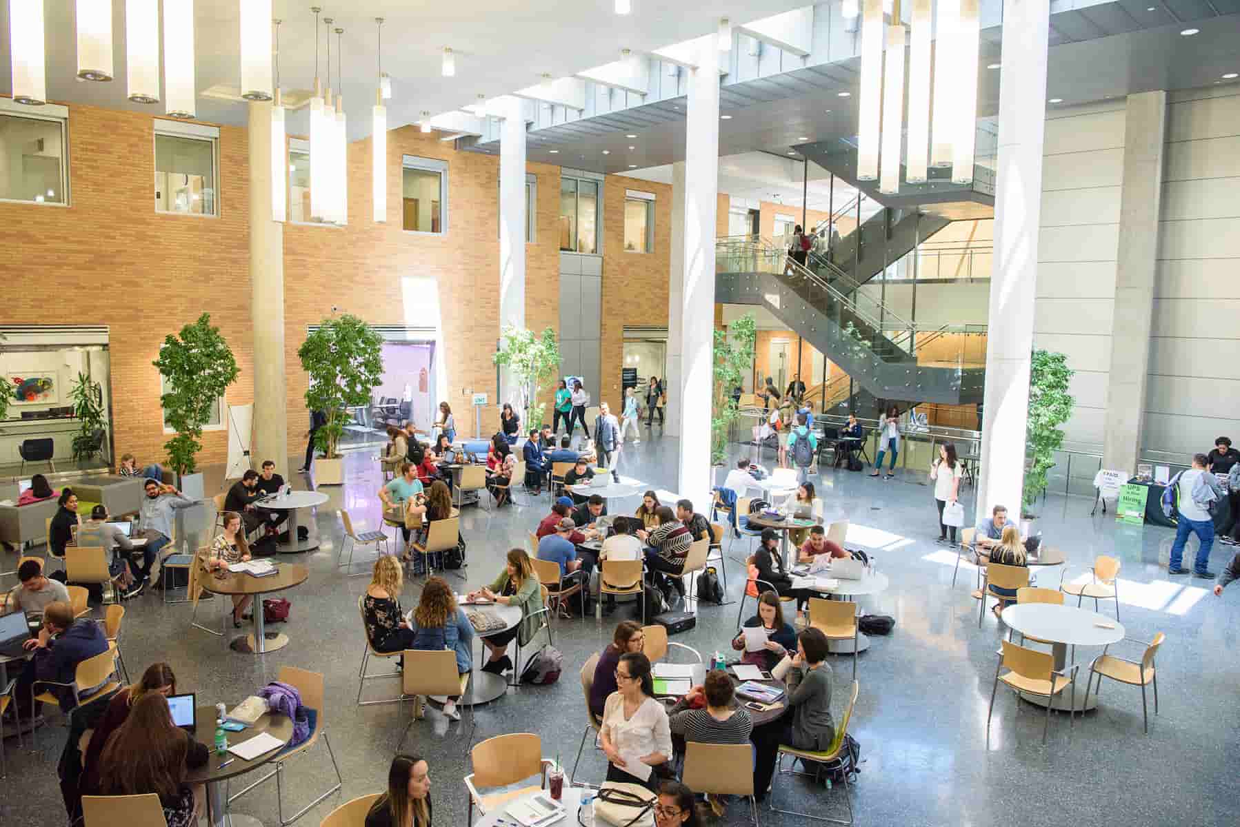 Students sit inside the G. Brint Ryan College of Business building, studying and hanging out