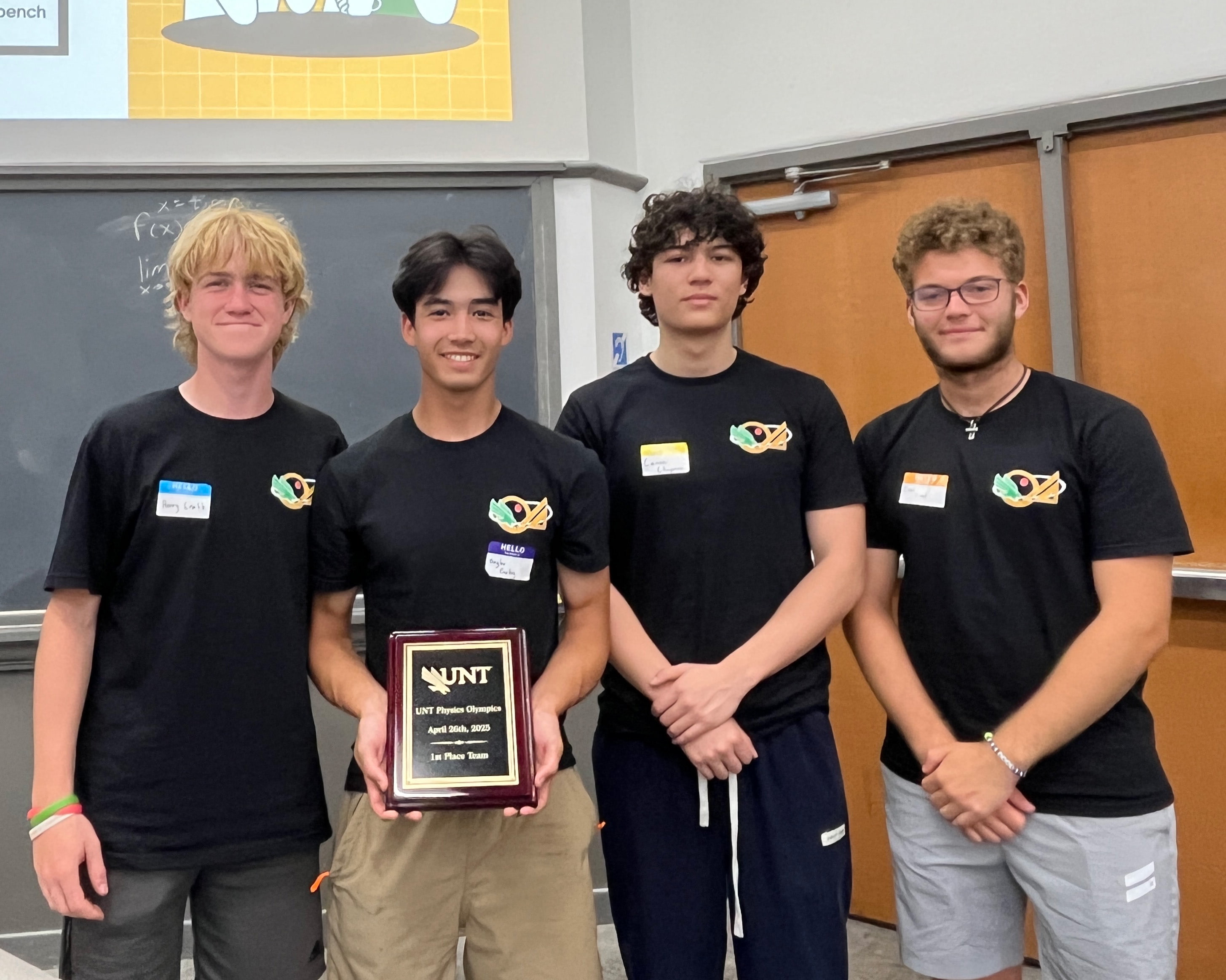 Four students hold the firs place plaque from the Physics Olympics