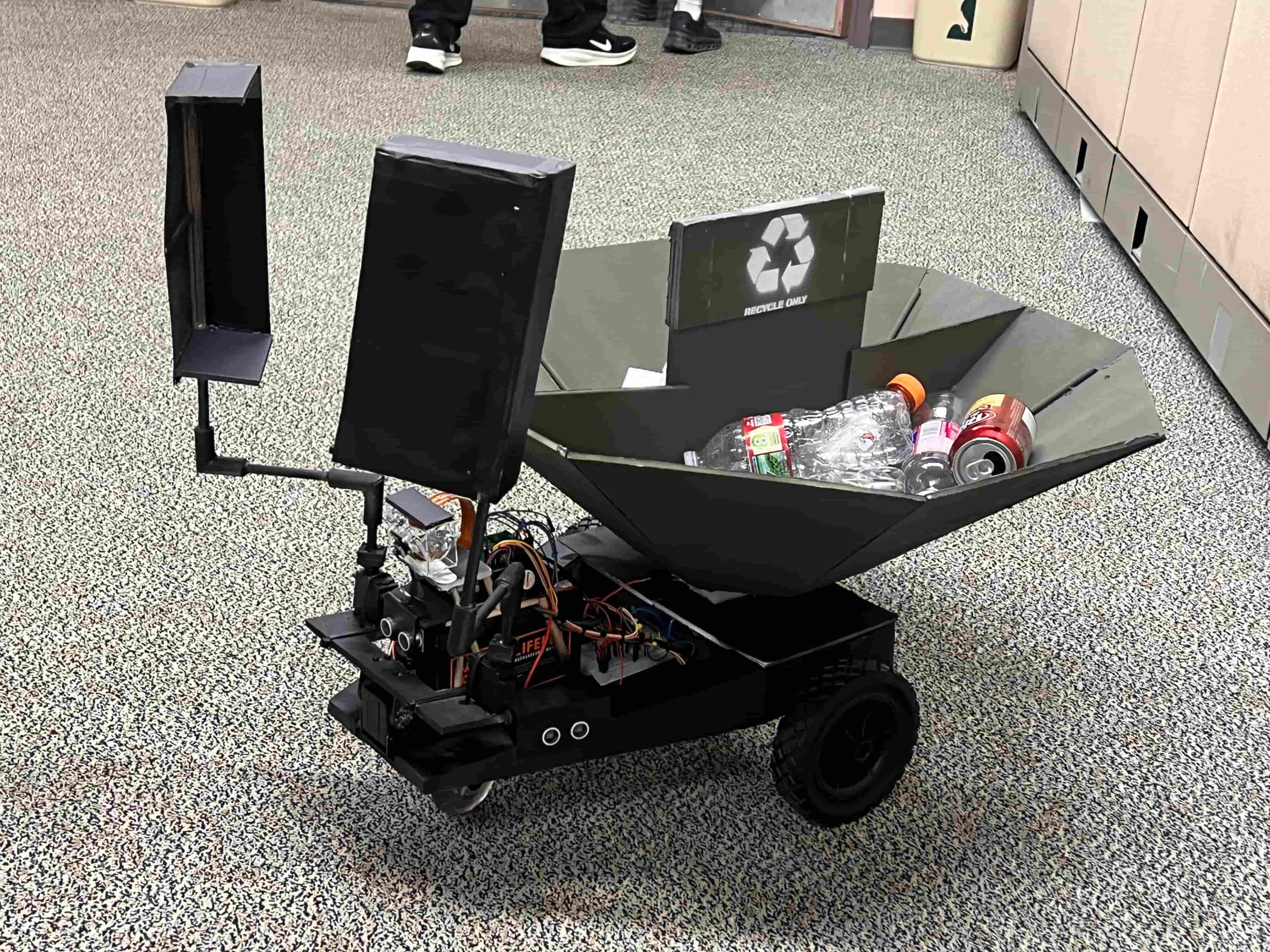 A robot with two scoopers attached to the front and a basket in the back for catching trash