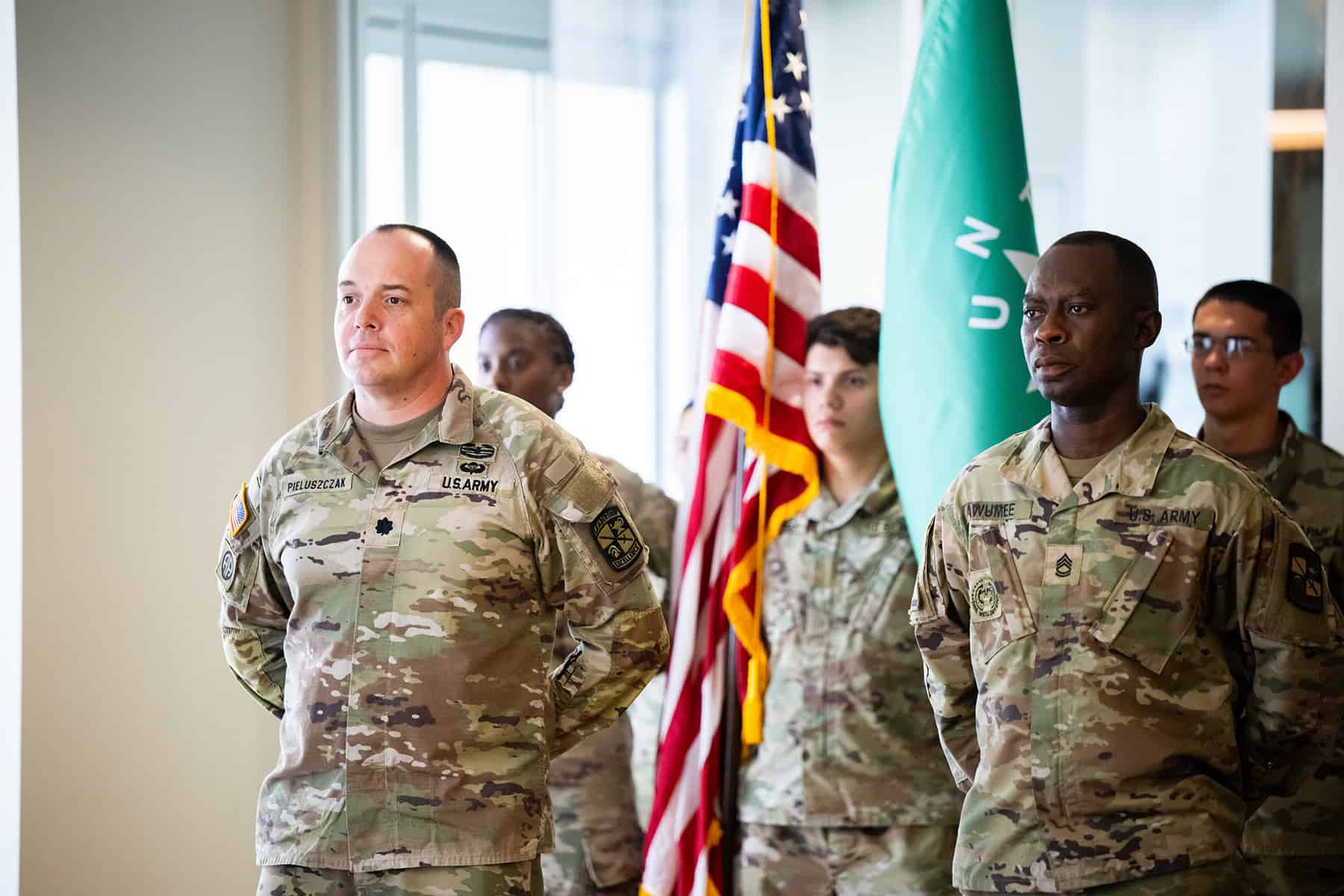 Army ROTC detachment members stand in formation in front of flags