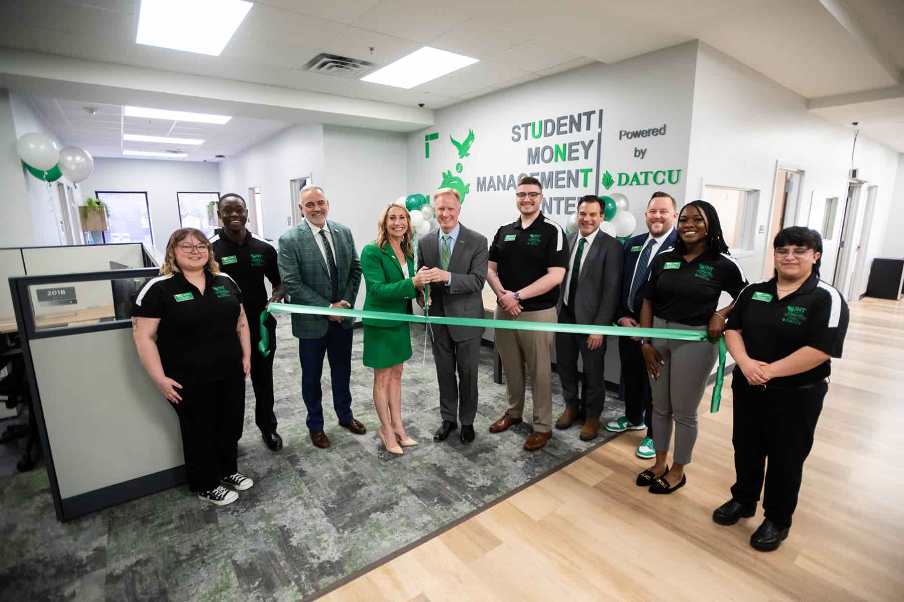 A group of people stands in front of UNT's Student Money Management Center, preparing to cut a green ribbon.