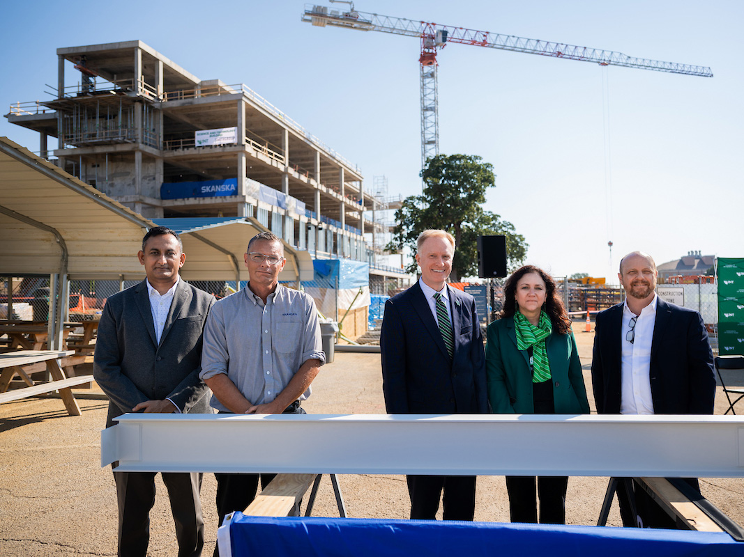 The Topping Off Ceremony for the Science, Research, and Techonology Building. The building stands in the background with a group of people in the front.