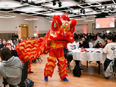 Person in a dragon costume going through a crowd of people at tables