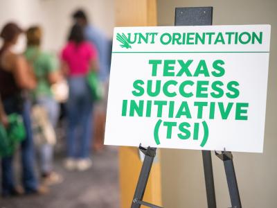 A line of students with a sign that says "UNT Orientation: Texas Success Initiaitive (TSI)"