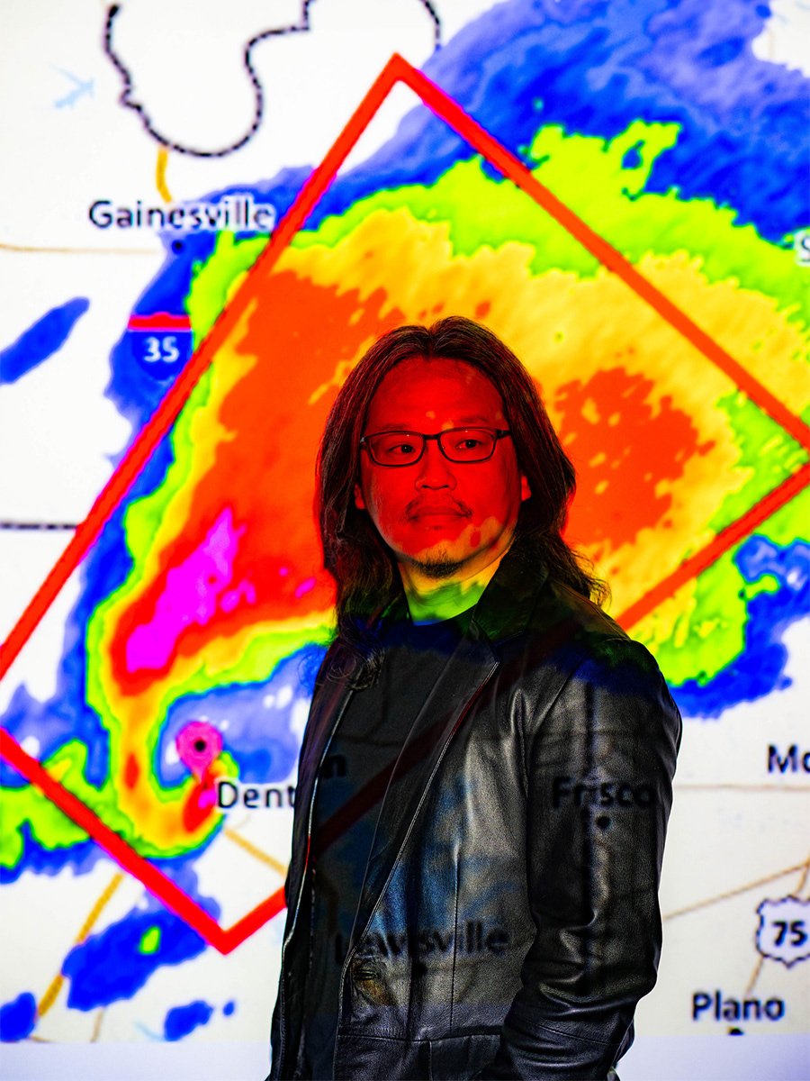 Tristan Wu posed in front of a weather map projection