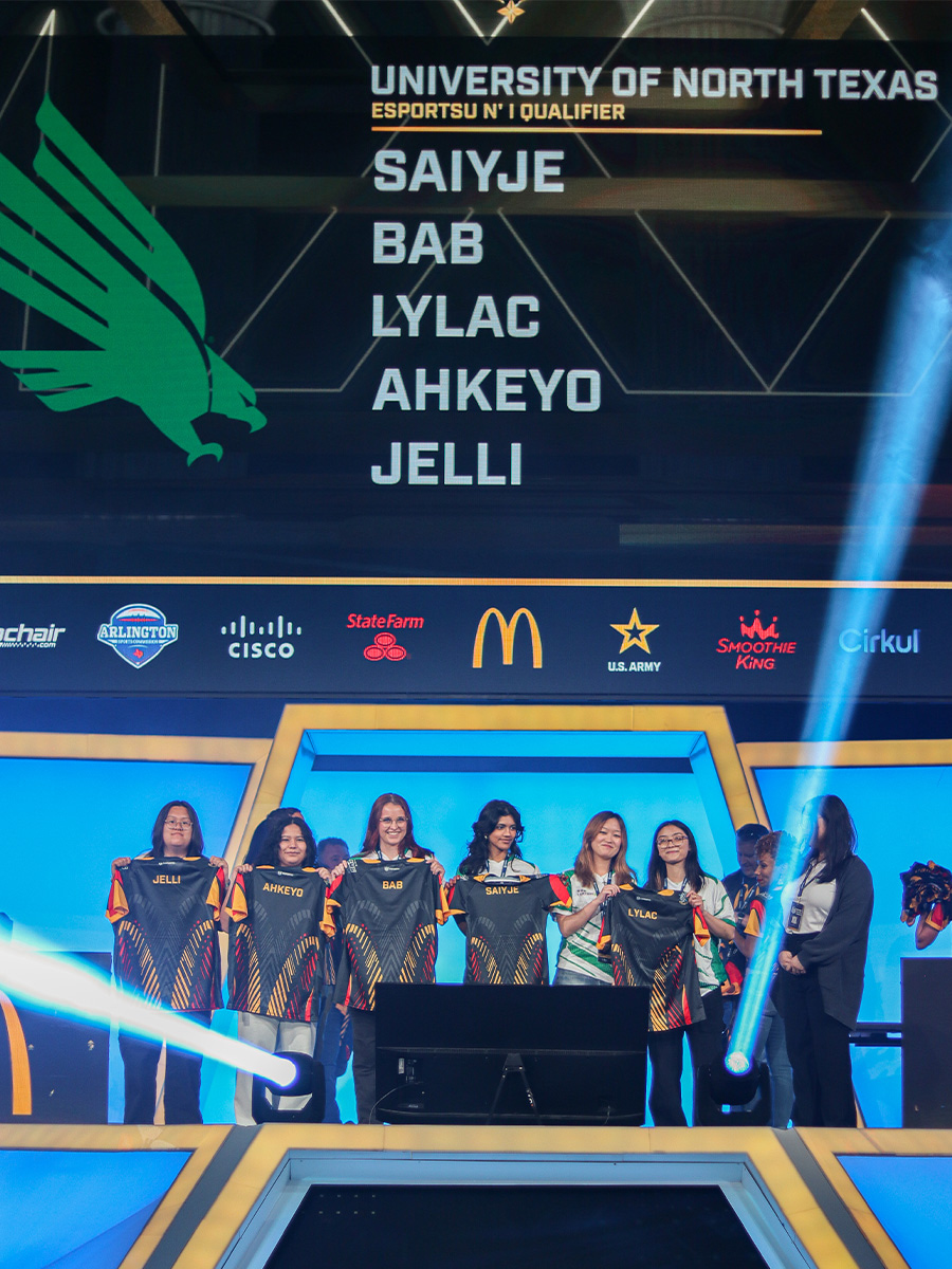 Teamates hold up their jerseys in front of a giant screen displaying their names