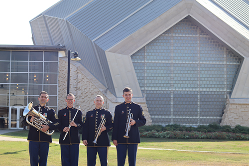 Four men in military dress hold instruments in front of the Murchison