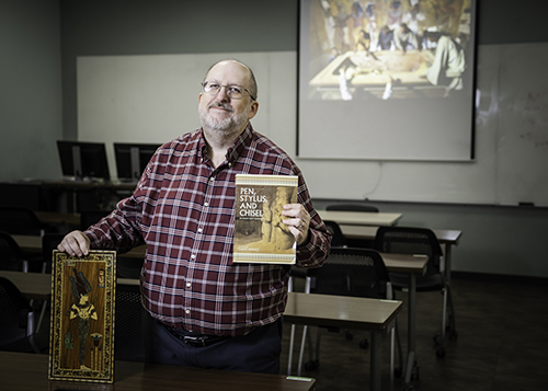 Walt Roberts, principal lecturer in UNT's Department of History, poses with books on Ancient Egypt