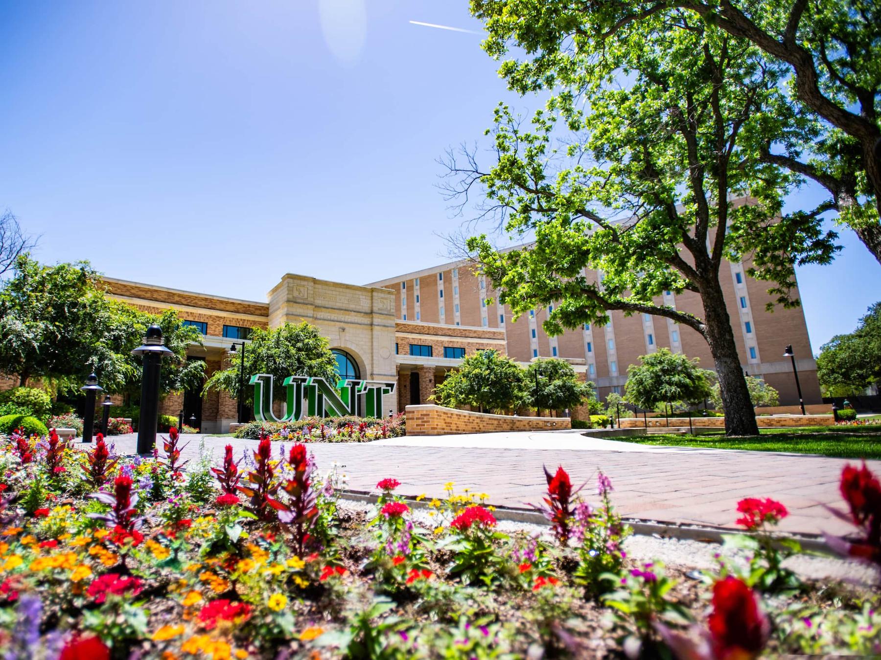 UNT Welcome Center with colorful flowers blooming in the foreground.