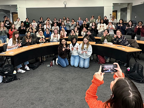 A large group of students posing in a classroom for a photo