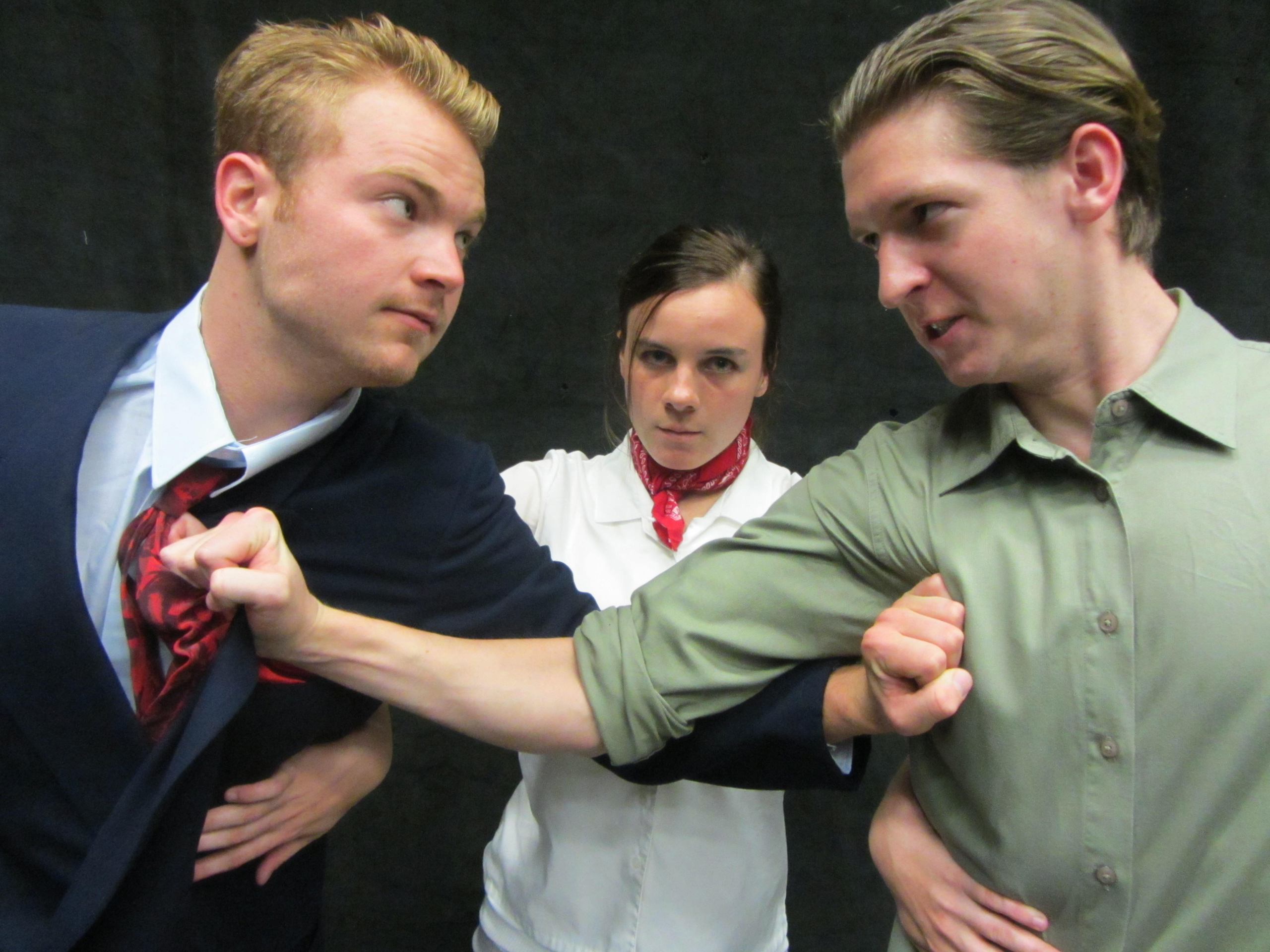 Two men seem prepared to fight, a woman tries to keep them separated.
