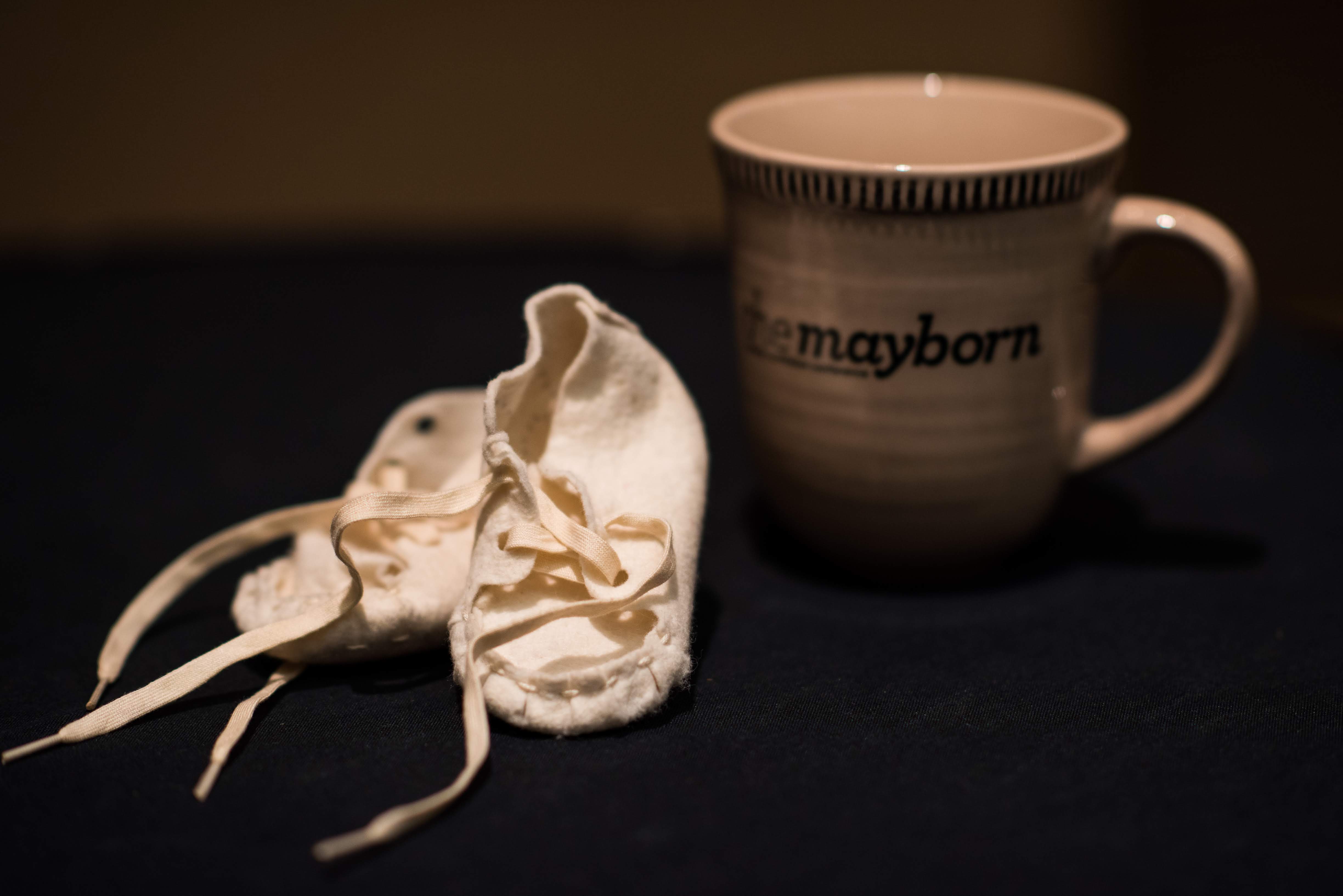 Photo of a pair of baby shoes next to a Mayborn coffee mug - representing the Mayborn Baby Shoes contest