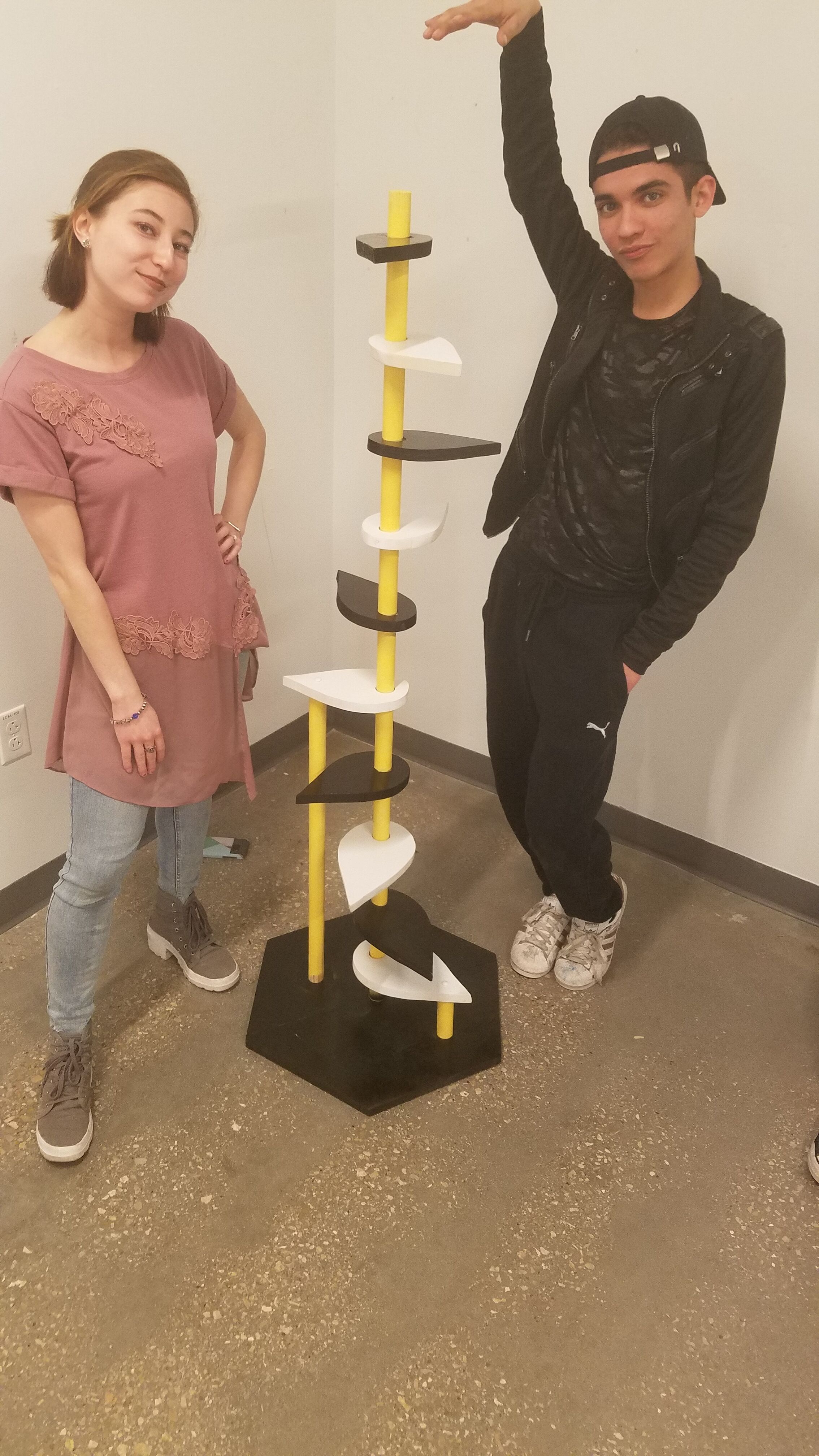 Art students Olivia Jennings and Ivy Cruz pose with their sculpture